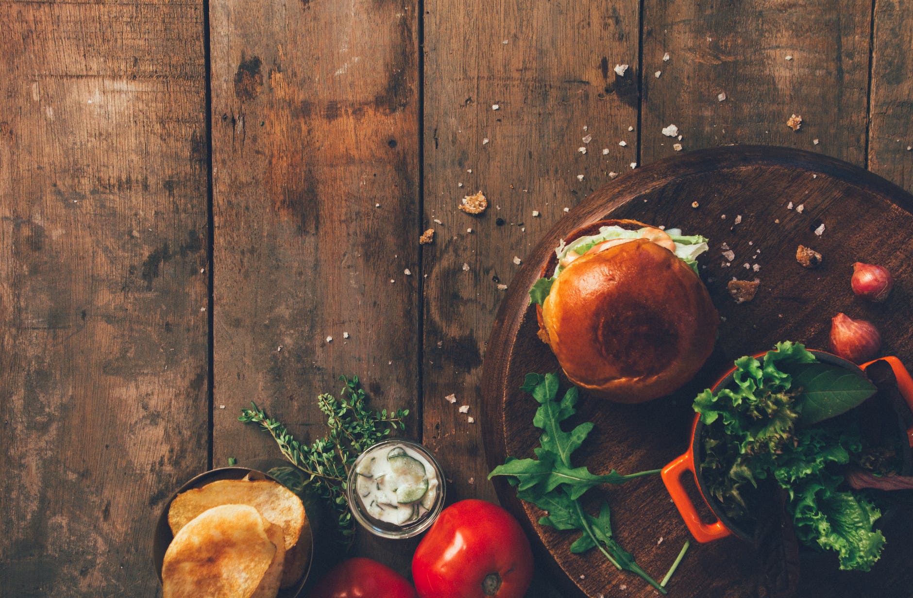 burger and vegetables placed on brown wood surface