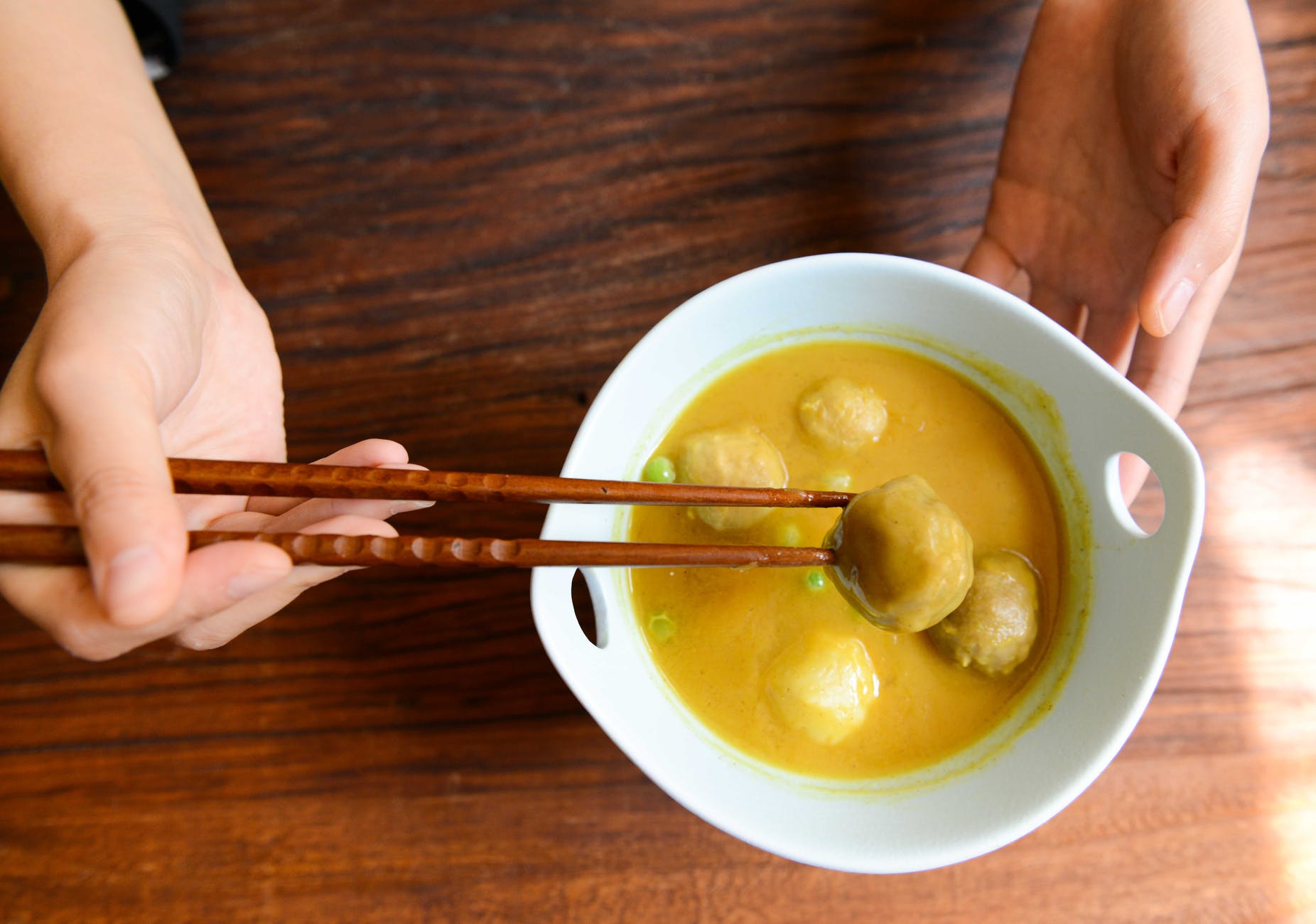 person holding chopsticks and white ceramic bowl